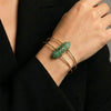 Gold bracelet with a green gemstone on a person's wrist against a black background