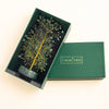 Decorative tree in a green box with 'Calm Nds' branding on a beige background