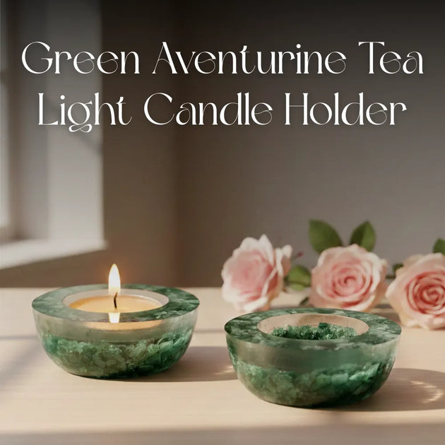 Green aventurine tea light candle holder with a lit candle on a surface with pink roses in the background.