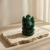 Green stone sculpture on a beige stone platform with soft lighting