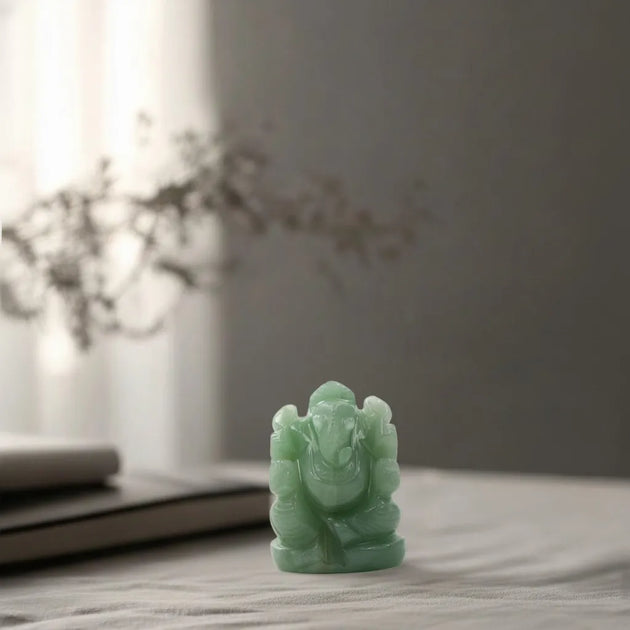 Green stone statue of a deity on a wooden surface with a blurred background