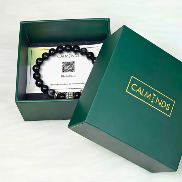 Black beaded bracelet in a green 'CALMINDS' box on a white background