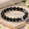 Black beaded bracelet on a stone surface with flowers