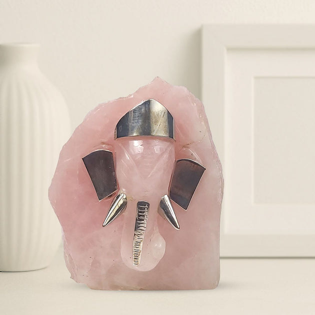 Decorative ganesha idol with pink crystal-like base and metallic accents on a neutral background