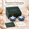 Two blue kyanite tea light holders with lit candles in front of a Calminds gift box and thank-you card