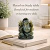 Green stone Ganesha statue on a book with text about its benefits for students or learning new skills.