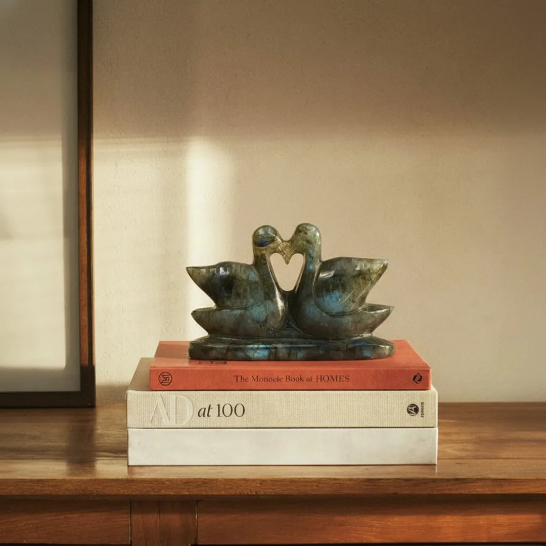 Bronze sculpture of two swans on books with a warm background