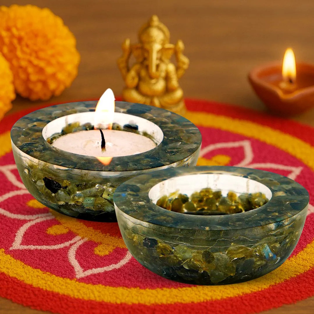 Two green stone candle holders with lit candles on a colorful fabric background.