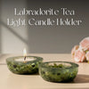Two Labradorite tea light candle holders with a lit candle on a neutral background.