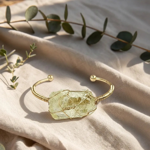 Gold bracelet with a green stone on a beige fabric background