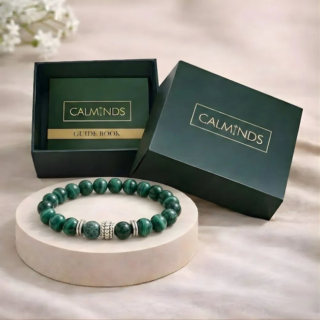 Green beaded bracelet on a white stand with 'CALMINDS' branded box in the background.