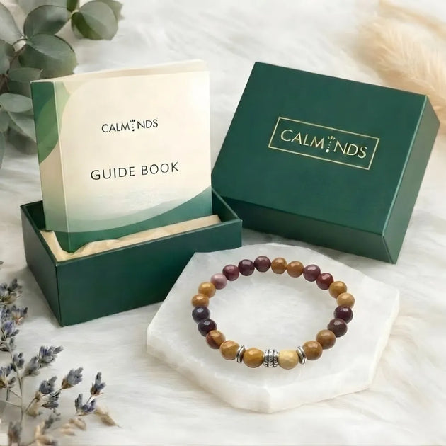 Beaded bracelet on a white surface with 'Calminds' packaging and guide book.
