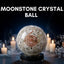 Moonstone crystal ball with a spiral design on a dark background with candles