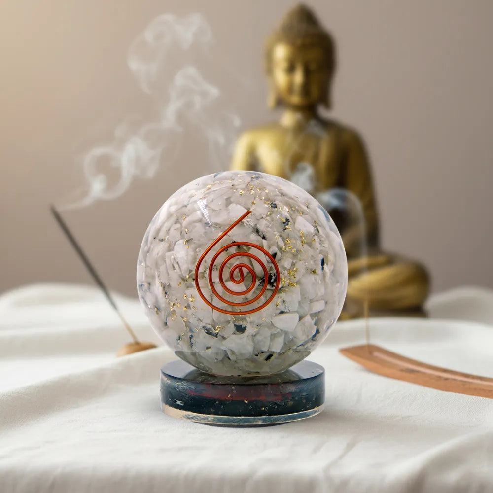Crystal ball with spiral design in front of a Buddha statue on a table.