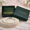 Pearl bracelet on a round wooden stand with 'Calminds' branded box and guide book in the background.