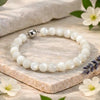 Pearl bracelet with a silver clasp on a wooden surface with flowers