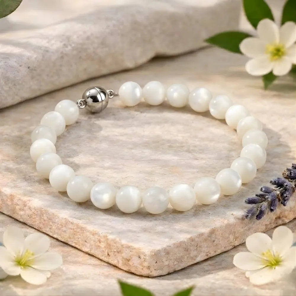 Pearl bracelet with a silver clasp on a wooden surface with flowers