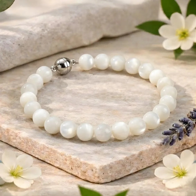 Pearl bracelet with a silver clasp on a wooden surface with flowers