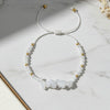 moonstone beaded thread bracelet with white stones and gold accents on a marble surface
