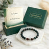 Beaded bracelet with 'Calminds' packaging and guide book on a soft surface.