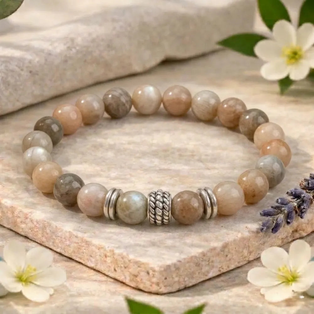 Beaded bracelet with silver accents on a stone surface with flowers