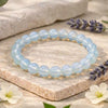 Blue beaded bracelet on a stone surface with lavender and flowers