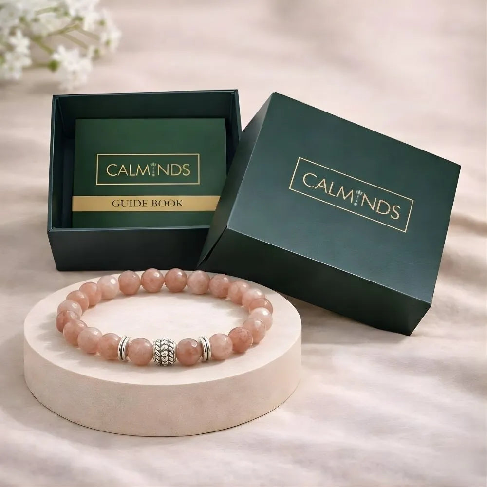 Pink beaded bracelet on a white stand with 'CALMINDS' branded box in the background.