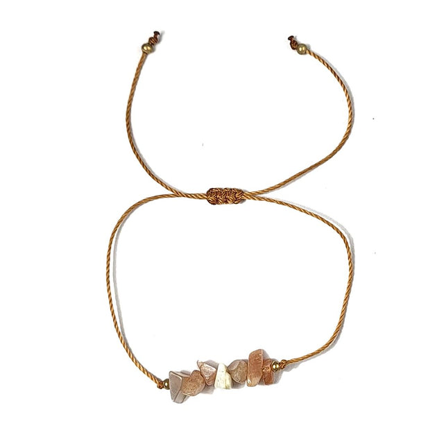 thread bracelet with peach stone beads on a white background
