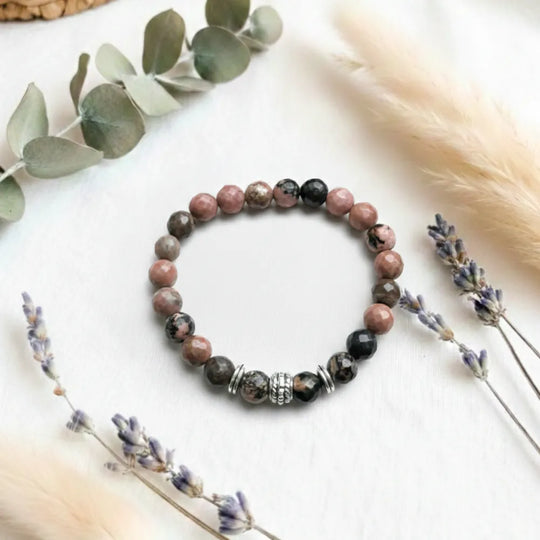 Beaded bracelet on a light surface with eucalyptus and lavender.