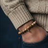 Close-up of a hand wearing a beaded bracelet with a neutral background