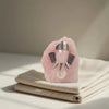 Pink crystal with metallic elephant figure on a beige surface