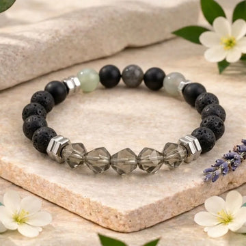 Black and gray beaded bracelet on a stone surface with flowers