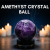 Amethyst crystal ball with candles in the background on a dark surface