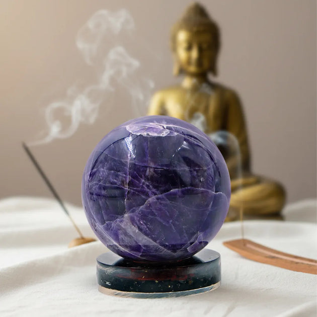 Purple crystal ball on a stand with a gold Buddha statue in the background