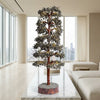 Decorative tree on a marble table in a modern living room with large windows.