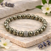 Bracelet with pyrite beads on a stone surface with flowers