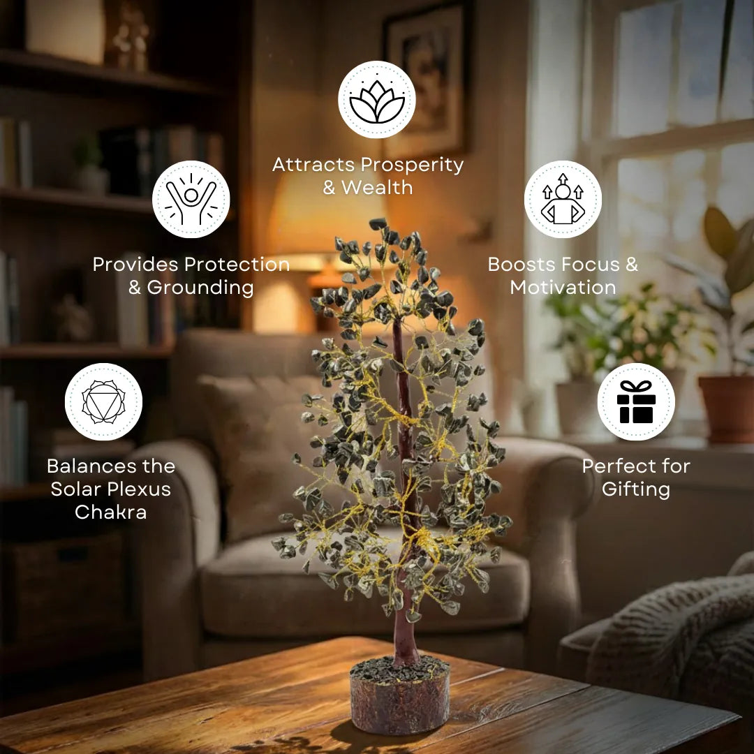 A small decorative tree with gray-green leaves and yellow string lights sits on a wooden table in a warmly lit living room. White circular icons with text overlays describe purported benefits such as attracting prosperity, providing protection, boosting focus, balancing the solar plexus chakra, and being perfect for gifting.