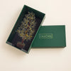 A crystal tree ornament displayed inside an open dark green gift box next to its lid, which features the brand name 'CALM NDS'.