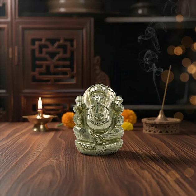 Decorative Ganesh statue on a wooden table with incense and candle in the background