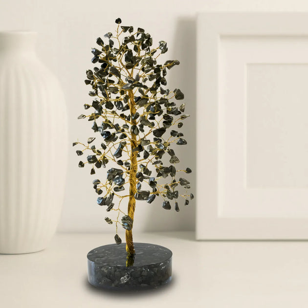 Decorative tree with black and gold leaves on a dark base against a white background