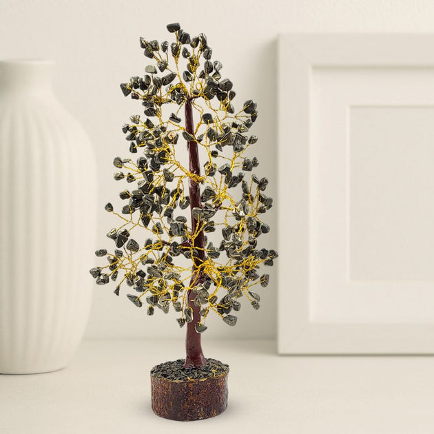  pyrite tree with black stones surrounded, wooden base, and gold wiring on a neutral background