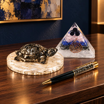 Pyrite turtle on a selenite plate, orgonite pyramid and pyrite pen on a wooden desk