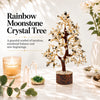 Rainbow moonstone crystal tree on a marble table with a lit candle and crystal points