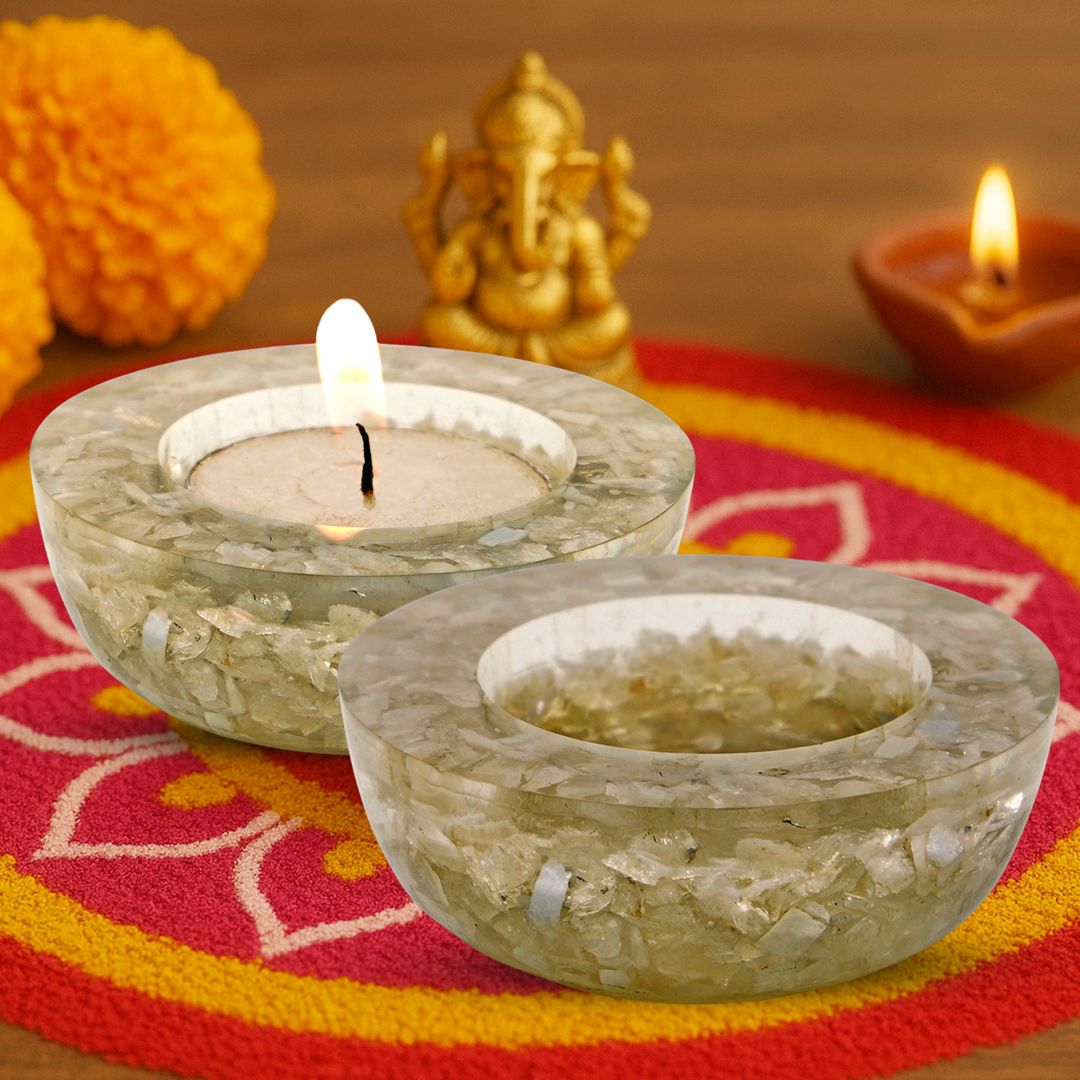 Two stone candle holders with lit candles on a colorful fabric background.