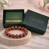 Brown beaded bracelet on a wooden stand with 'CALMINDS' branded box and guide book in the background.