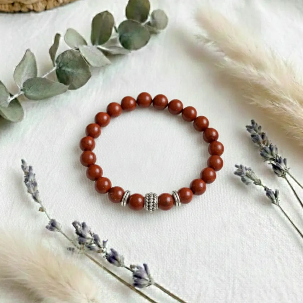 Brown beaded bracelet with silver accents on a white surface with decorative elements