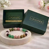 Colorful beaded bracelet on a white stand with 'Calminds' branded box and guide book in the background.