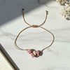 thread bracelet with pink rhodonite stones on a light surface
