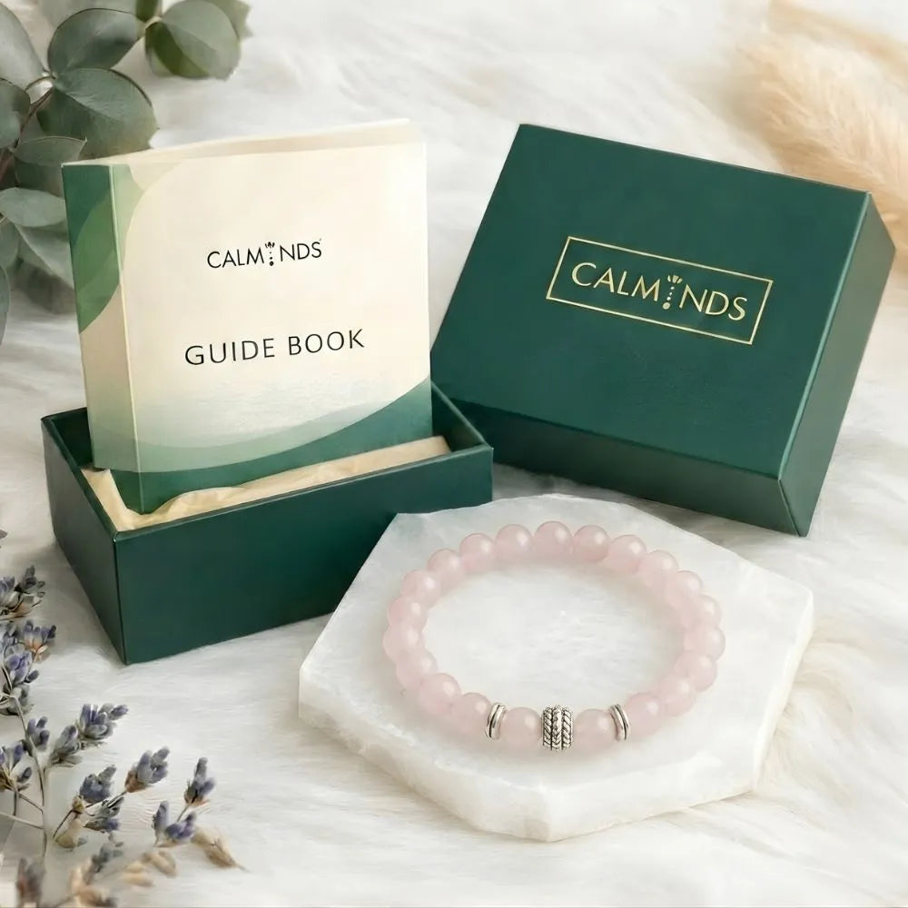 Pink bracelet with silver accents on a white stand, surrounded by 'Calminds' branded items.
