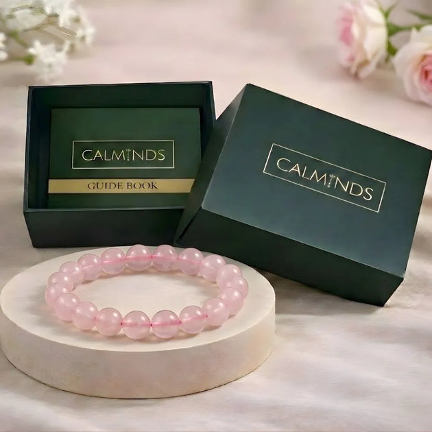 Pink beaded bracelet on a white stand with 'CALMINDS' branded box in the background.